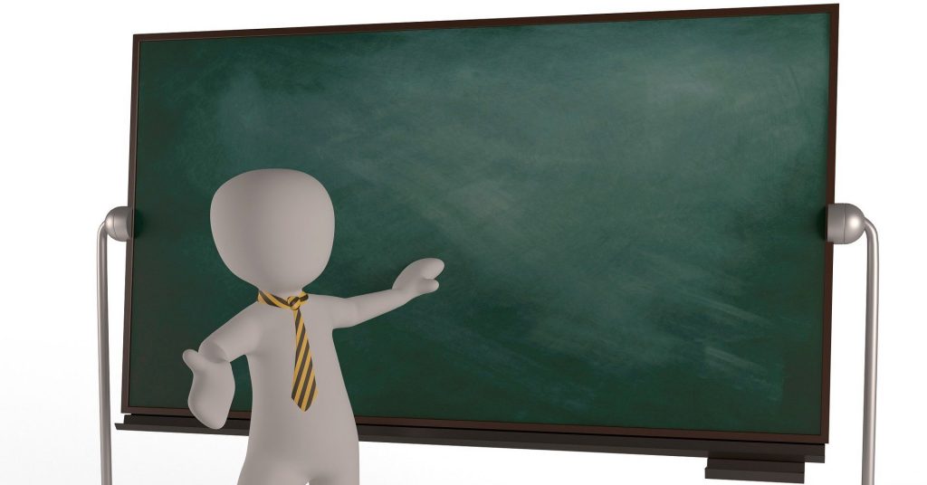 The picture shows an univerity teacher in front of a blackboard with an explanatory gesture