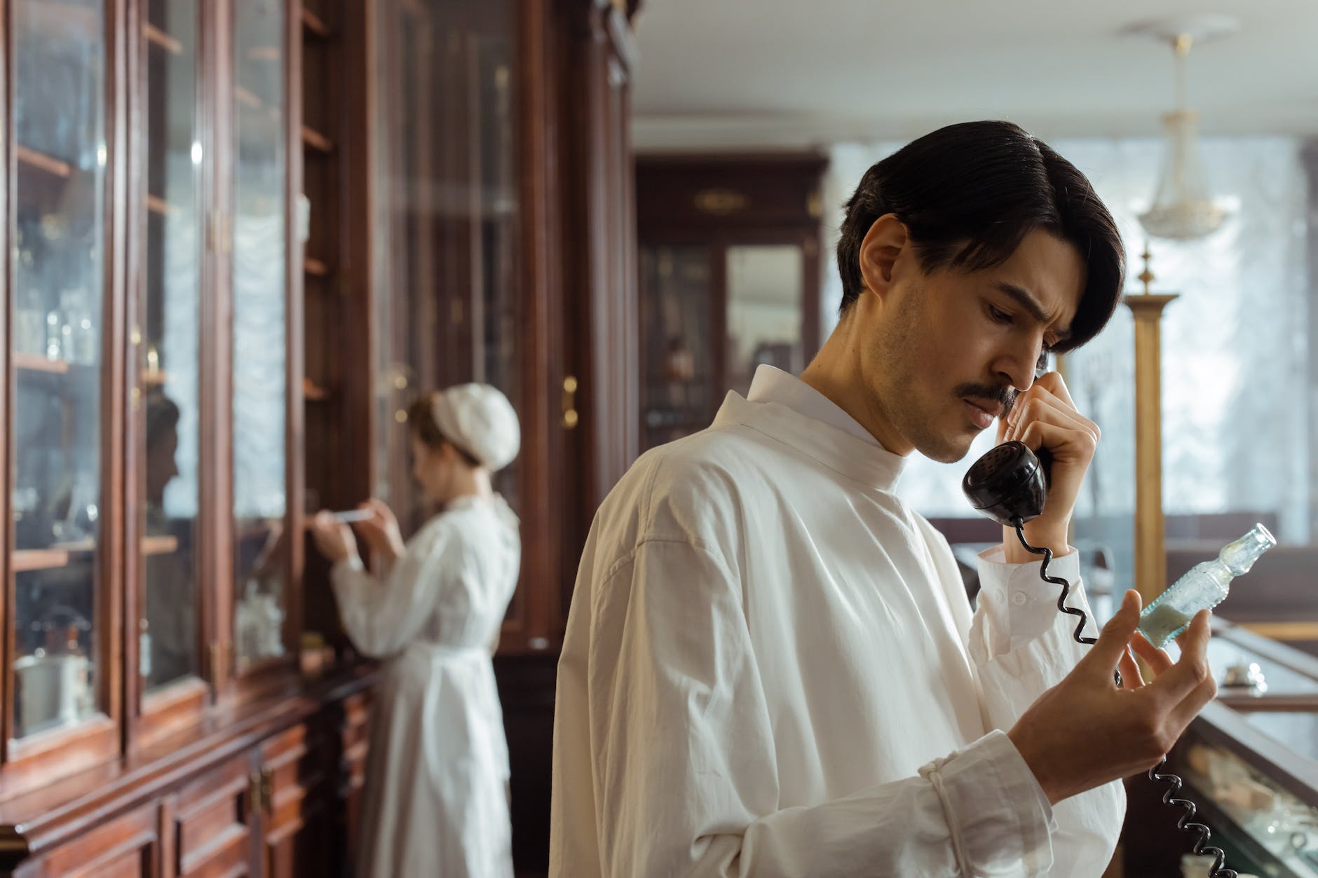 a man talking on the telephone while holding a flask