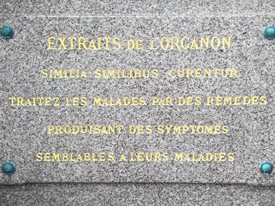 The picture shows a memorial plaque to Hahnemann's tomb in Paris with key sentences from the Organon