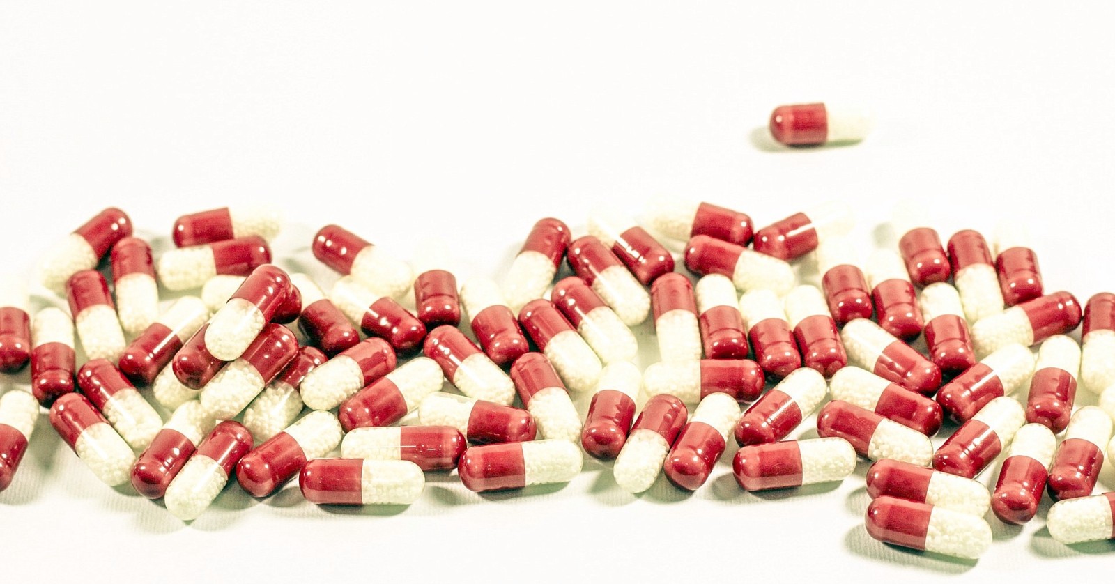 Red-white medical capsules filled with a white substance spread on a table